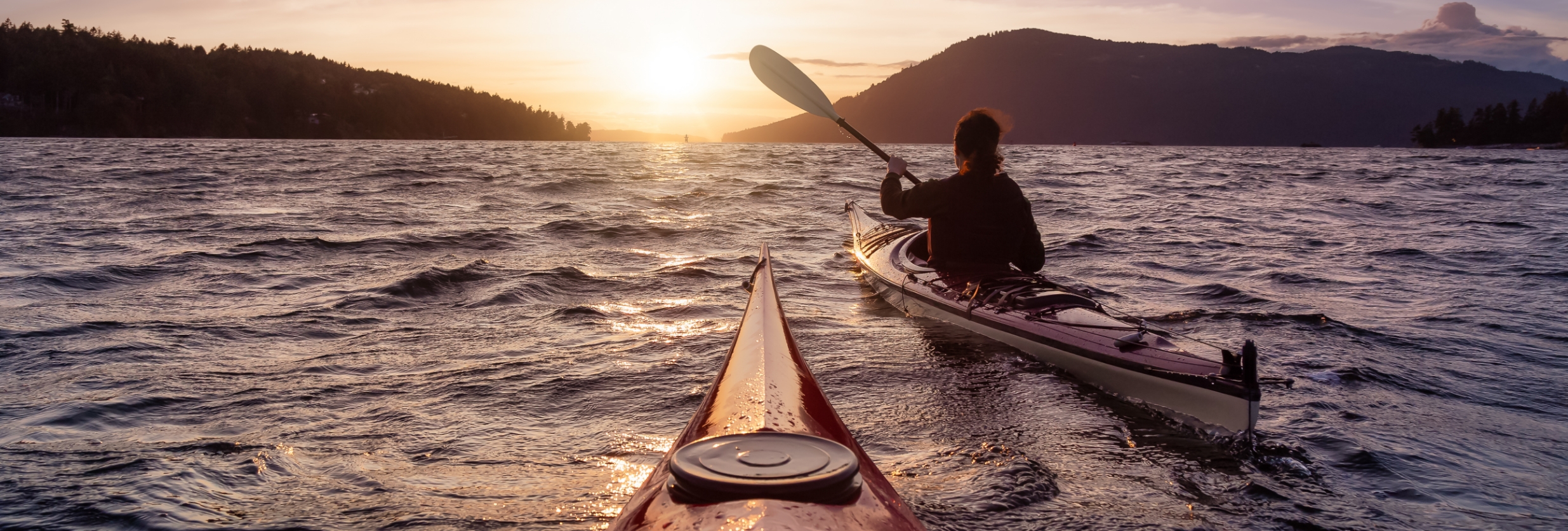 2 people kayaking in the ocean at sunset